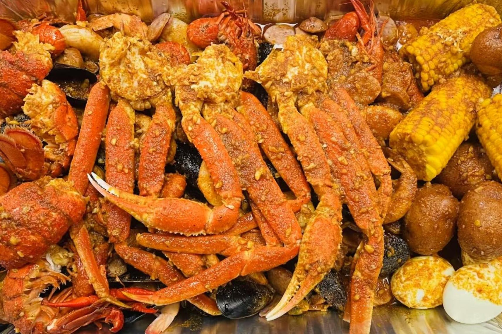 Seafood boil piled high with snow crab legs, corn on the cob and hush puppies